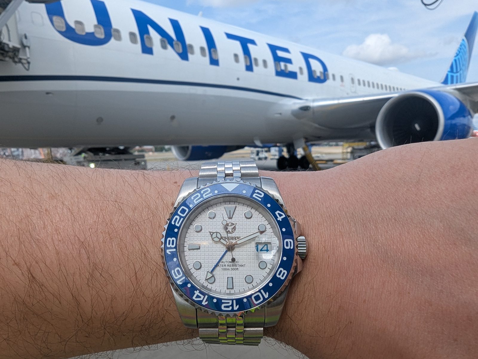 Somerada GMT on the wrist in front of a United aircraft